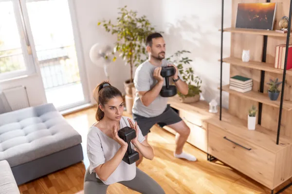 Coaching à domicile en couple, exercices de squats avec haltères pour remise en forme